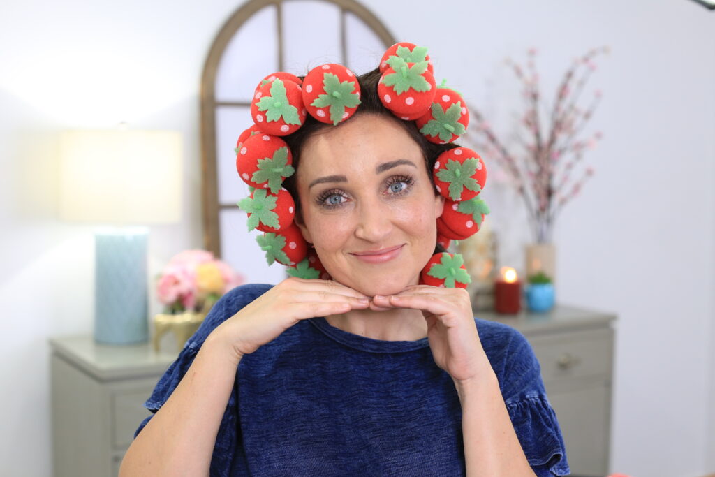Portrait of woman sitting indoors wearing 'Strawberry Foam Curlers' product in her hair