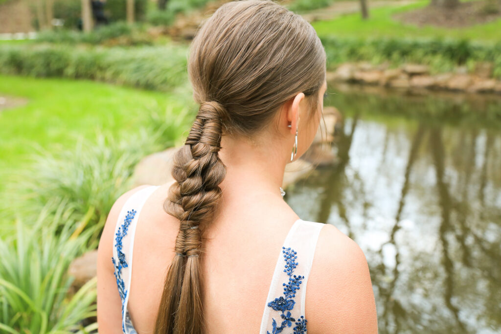 Side view of burnette girl with standing by pond with low infinity braid combo hairstyle.