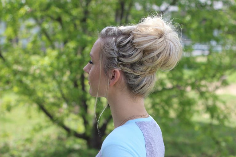 Side view of girl with blue and purple shirt standing outside modeling "Waterfall Bun" hairstyle 