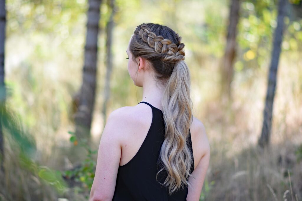 Side view of a young girl wearing a black shirt standing in the meadow modeling "Twisted Dutch Braid Ponytail" hairstyle