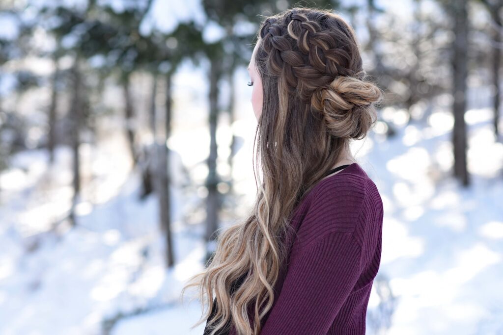 Side view of girl standing outside in a snowy forest modeling the "Double Dutch Half-Up" hairstyle