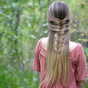 Back view of girl with long hair standing in the wood modeling "Mermaid Fishtail" hairstyle