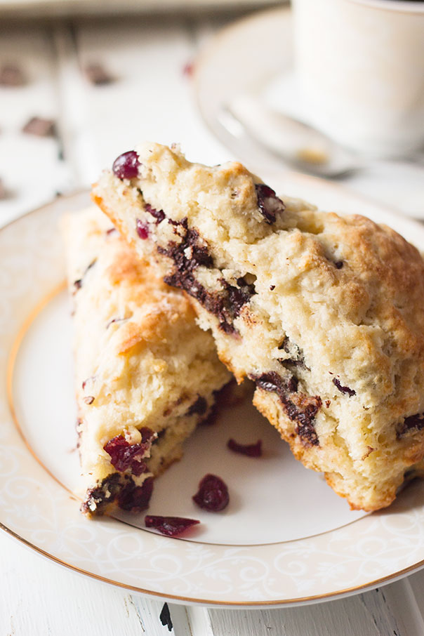 Two cherry and chocolate scones stacked and placed on a white plate