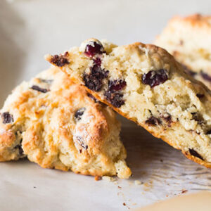 Three cherry and chocolate scones placed on a white parchment paper