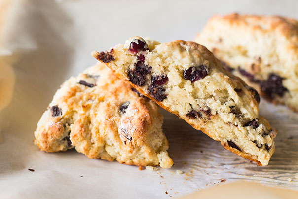 Three cherry and chocolate scones placed on a white parchment paper 