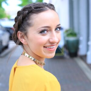 Girl with yellow shirt standing outside modeling the " Double Dutch Buns" hairstyle