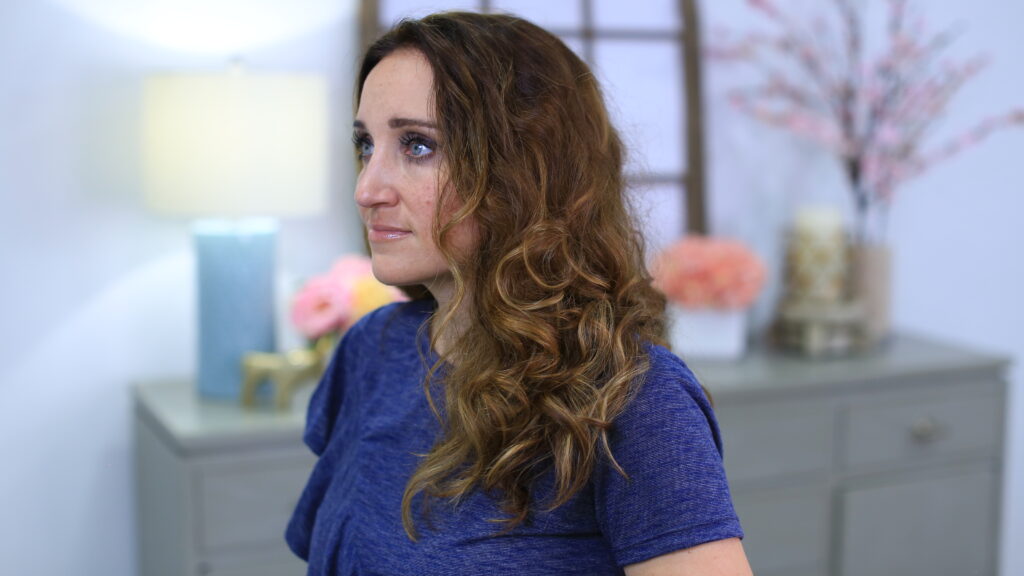 Side view of a woman with curly hair sitting in her room