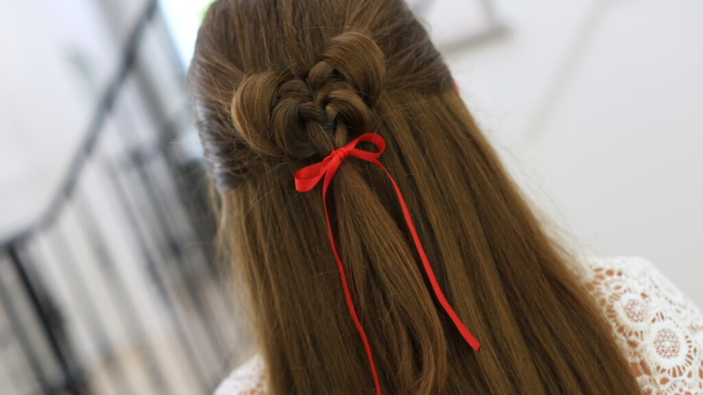 Back view of girl standing indoors wearing a red ribbon in her hair modeling the "Butterfly Tieback" hairstyle