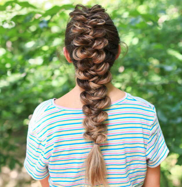 back view of girl with striped shirt standing outside modeling the "CGH Wrap Braid" hairstyle