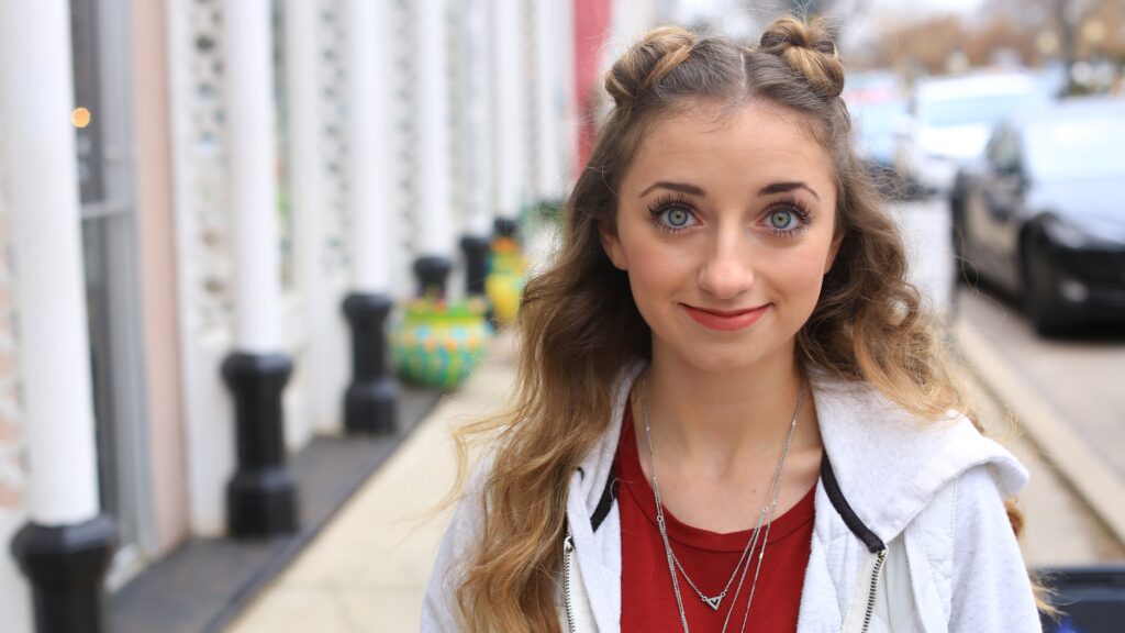 Portrait of a young girl with a long hair smiling standing on sidewalk