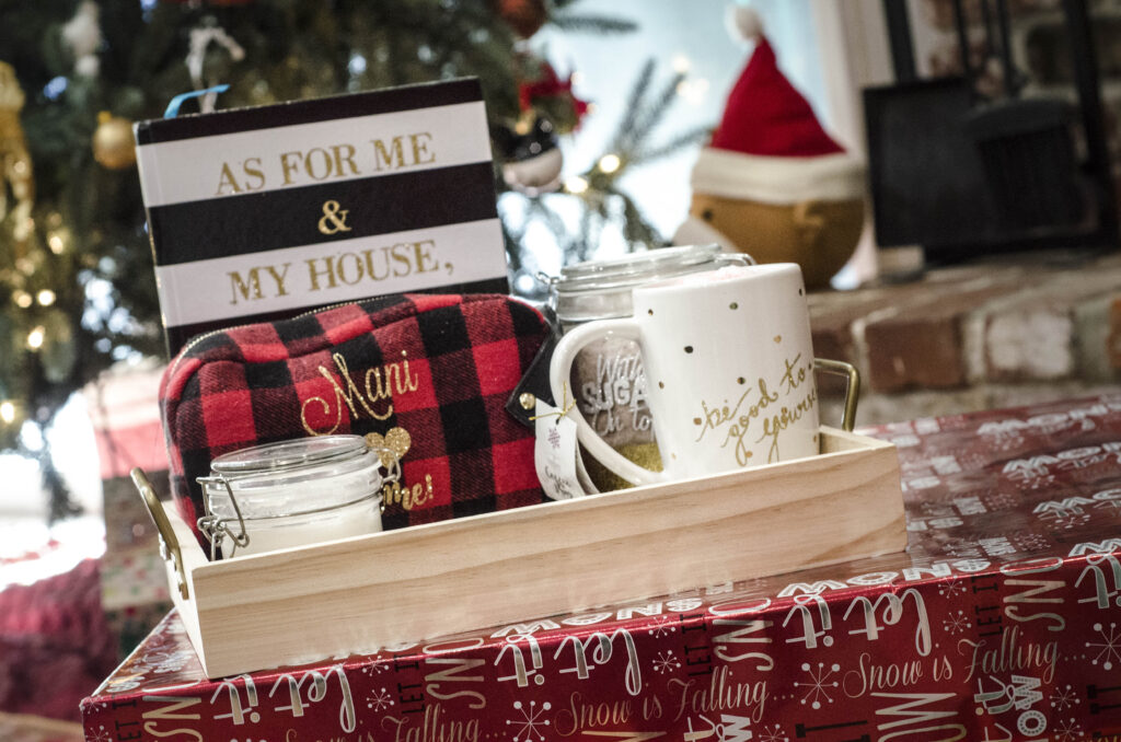 A notebook, makeup bag, coffee mug, and sugar place in a serving tray by the Christmas tree 