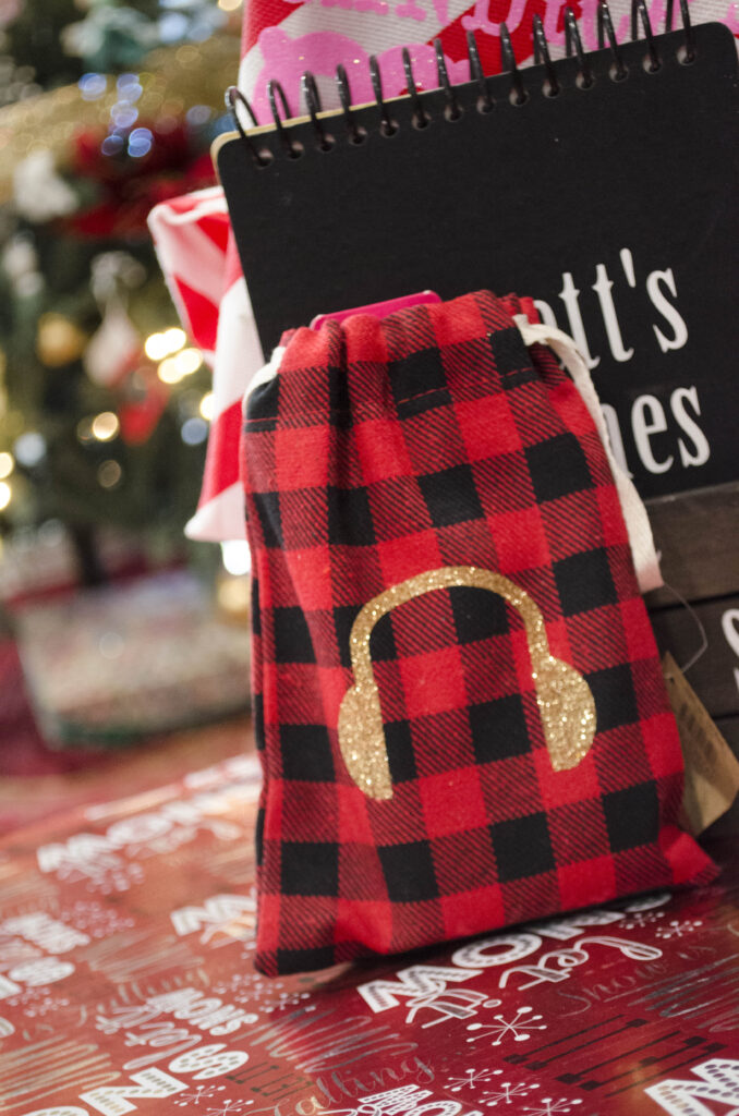 Red and black plaid bag with a gold 'headphones' icon, placed in front of a black sketch journal