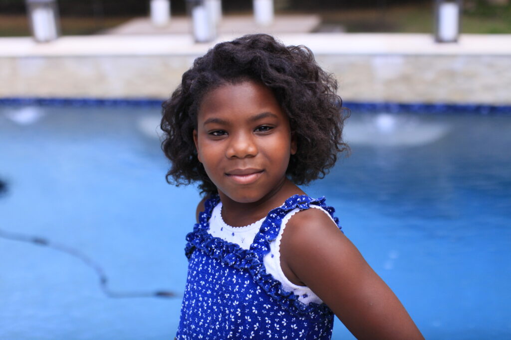 little girl standing by the pool smiling