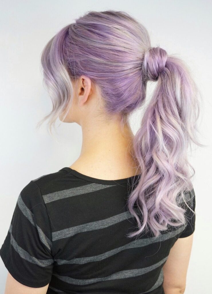 Side view of girl with lavender modeling a high ponytail in front of a white background