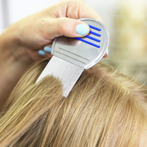 Mom using comb to brush out lice out of blonde daughter's hair