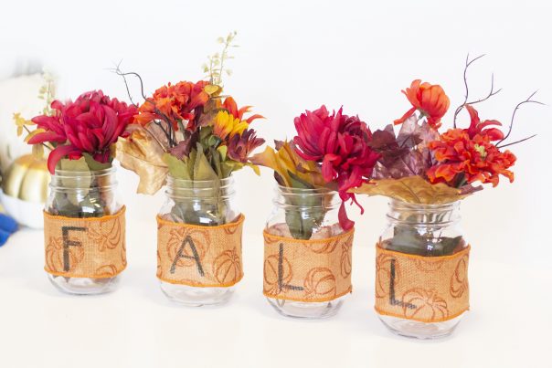 Fall flowers place inside mason jars wrapped with fall themed ribbon
