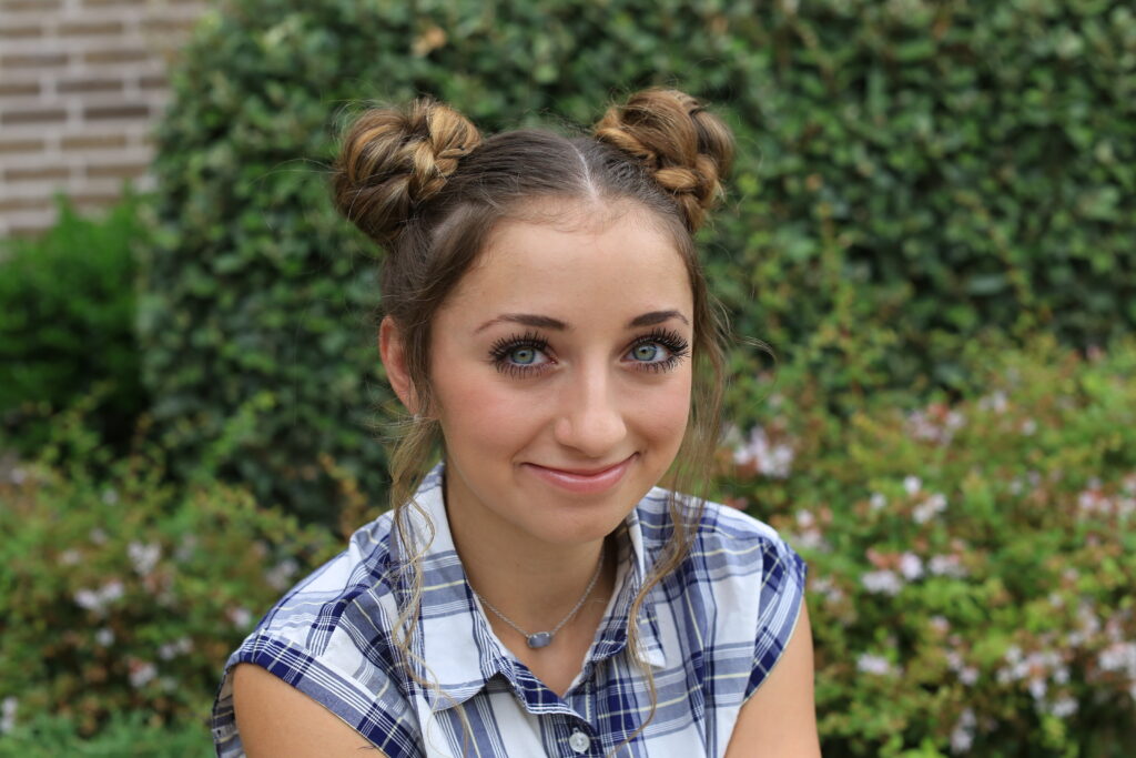 Girl sitting outside modeling Double Braided Bun for back to school hairstyles