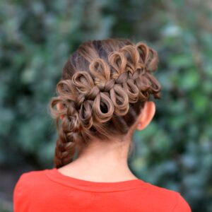 (Back) Young girl wearing a red shirt outside modeling Diagonal Bow Braid | Popular Hairstyles