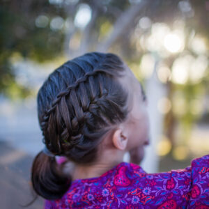 Side view of a young girl playing outside modeling "Gym Braid Combo" hairstyle