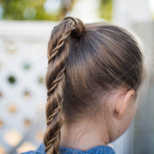 Close-up back view of little girl standing outside modeling "Twist Wrap Ponytail"