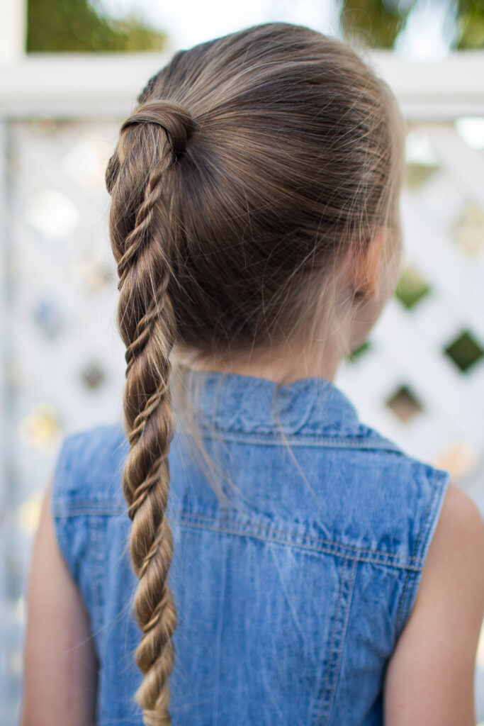 Close-up back view of little girl standing outside modeling "Twist Wrap Ponytail"