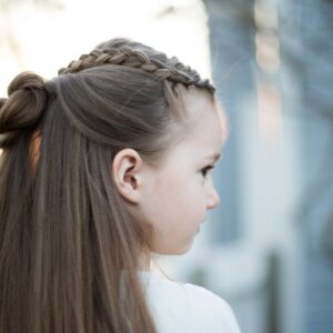 Side profile for a young girl standing outside modeling "Braided Bun Combo" hairstyle