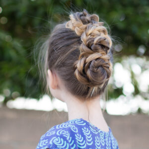 Side view of a little girl with long hair standing outside modeling "Triple Bun Updo" hairstyle