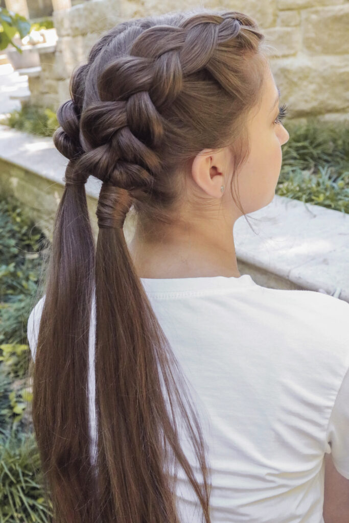 Profile shot of girl with long brown hair standing outside modeling the "Double Dutch Wrap" hairstyle
