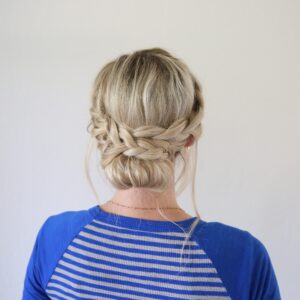 Back view of woman standing in front of a white background with a blue shirt modeling "French Lace Updo" hairstyle