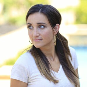 Portrait of a woman standing outside by the pool in a white shirt and pigtails