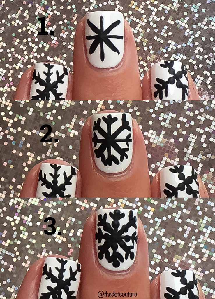 White painted nails with black snowflakes in front of glitter background