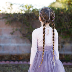 Back view of little girl standing outside in her tutu modeling "Banded Twist Braid" hairstyle