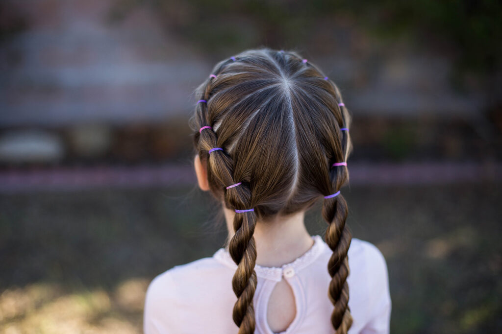 Close up back view of little girl standing outside modeling "Banded Twist Braid" hairstyle