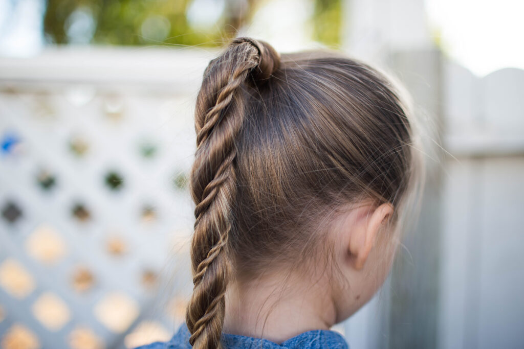 Close-up back view of little girl standing outside modeling "Twist Wrap Ponytail"