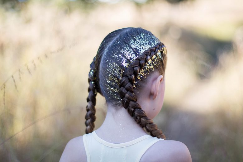 Back view of girl outside with gold glitter in her hair modeling "Dutch Glitter Braids" hairstyle 