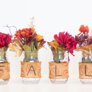 Fall flowers place inside mason jars wrapped with fall themed ribbon