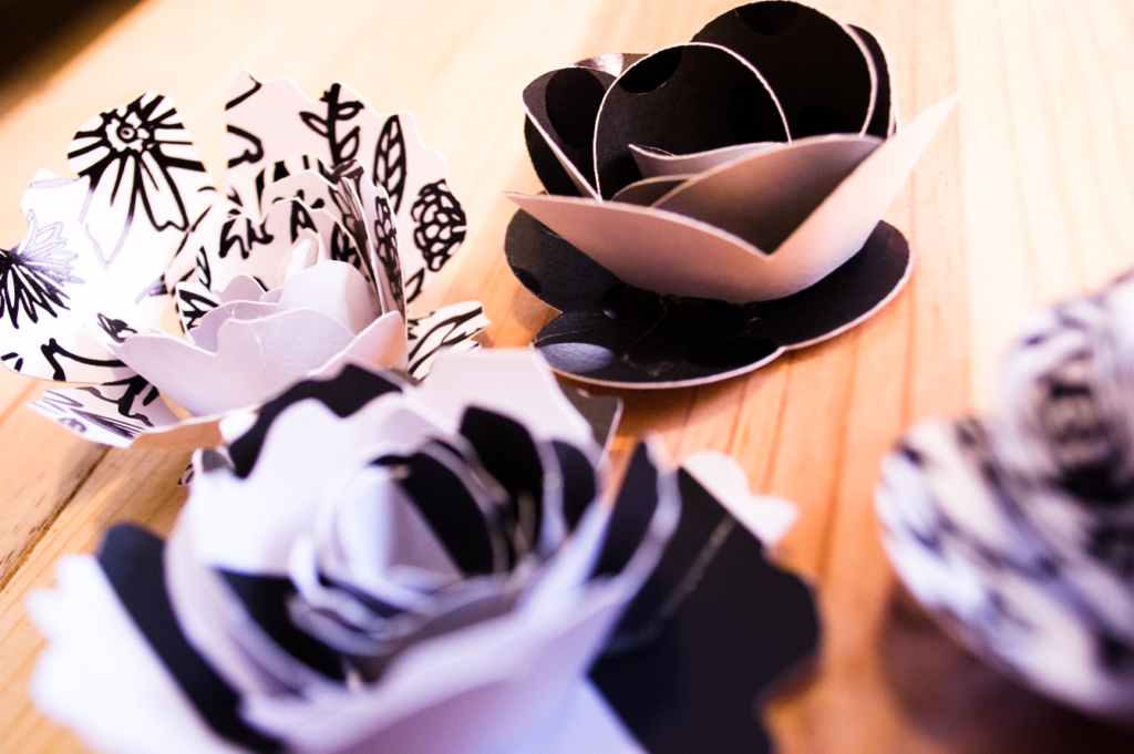 Black and white paper flowers place on top of a wooden table