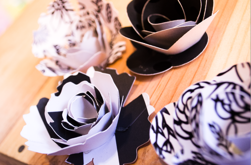 Black and white paper flowers place on top of a wooden table